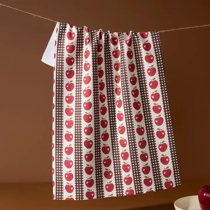 Towel with red apple pattern hanging on a line against a brown background
