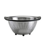 A stainless steel OXO 5QT colander with black handles and feet, featuring a round shape with perforations throughout.