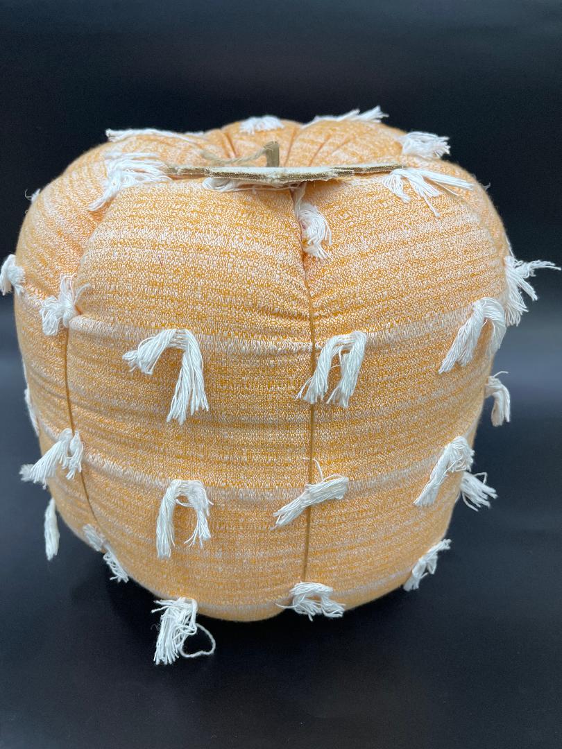 A decorative orange pumpkin with fringe detailing.