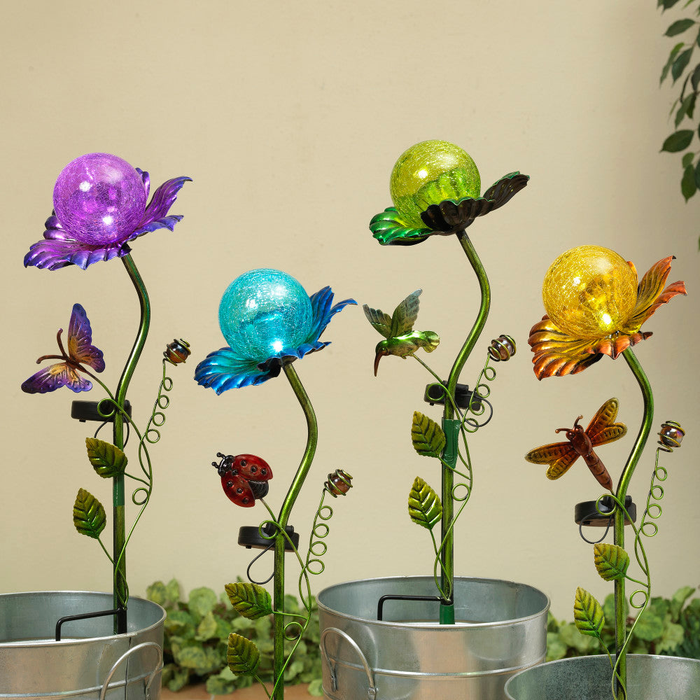 A solar lighted metal stake featuring a floral design with a purple, blue, and yellow globe at the top, mounted on a green stem with butterflies and ladybugs.