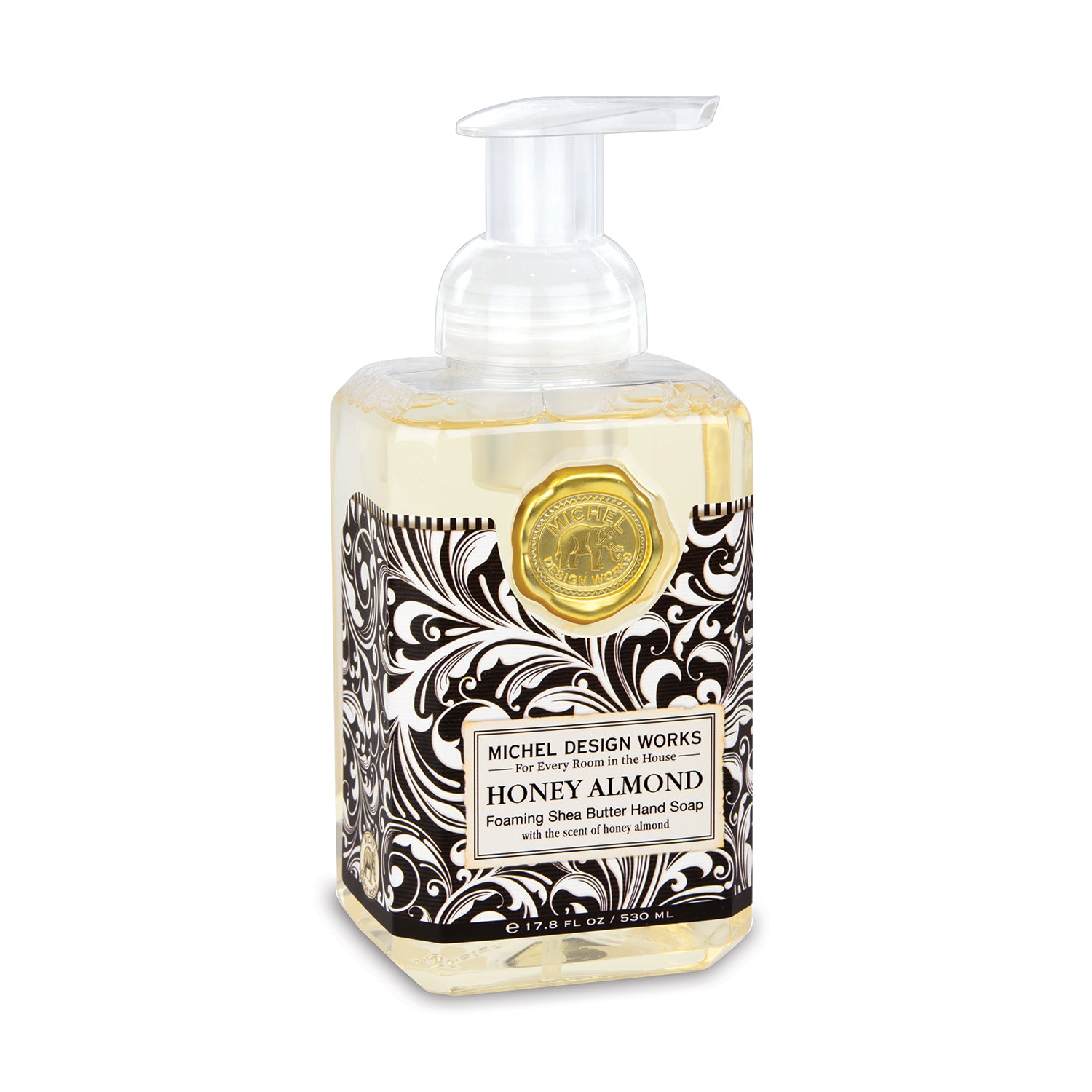 A clear pump bottle of MICHEL DESIGN WORKS Honey Almond Foaming Hand Soap with a black and white floral pattern label.