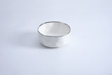 A white ceramic bowl with a black rim on a light background.