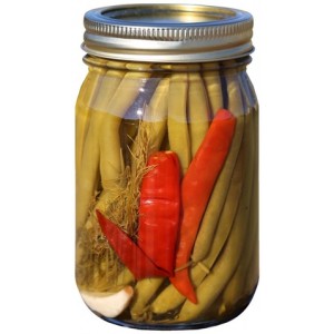 A jar of pickled green beans with visible red pepper and garlic cloves.