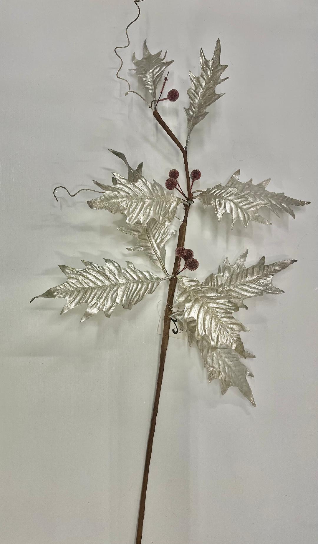 A metallic holly leaf spray with silver leaves and red berries on a brown stem, likely a decorative holiday ornament.