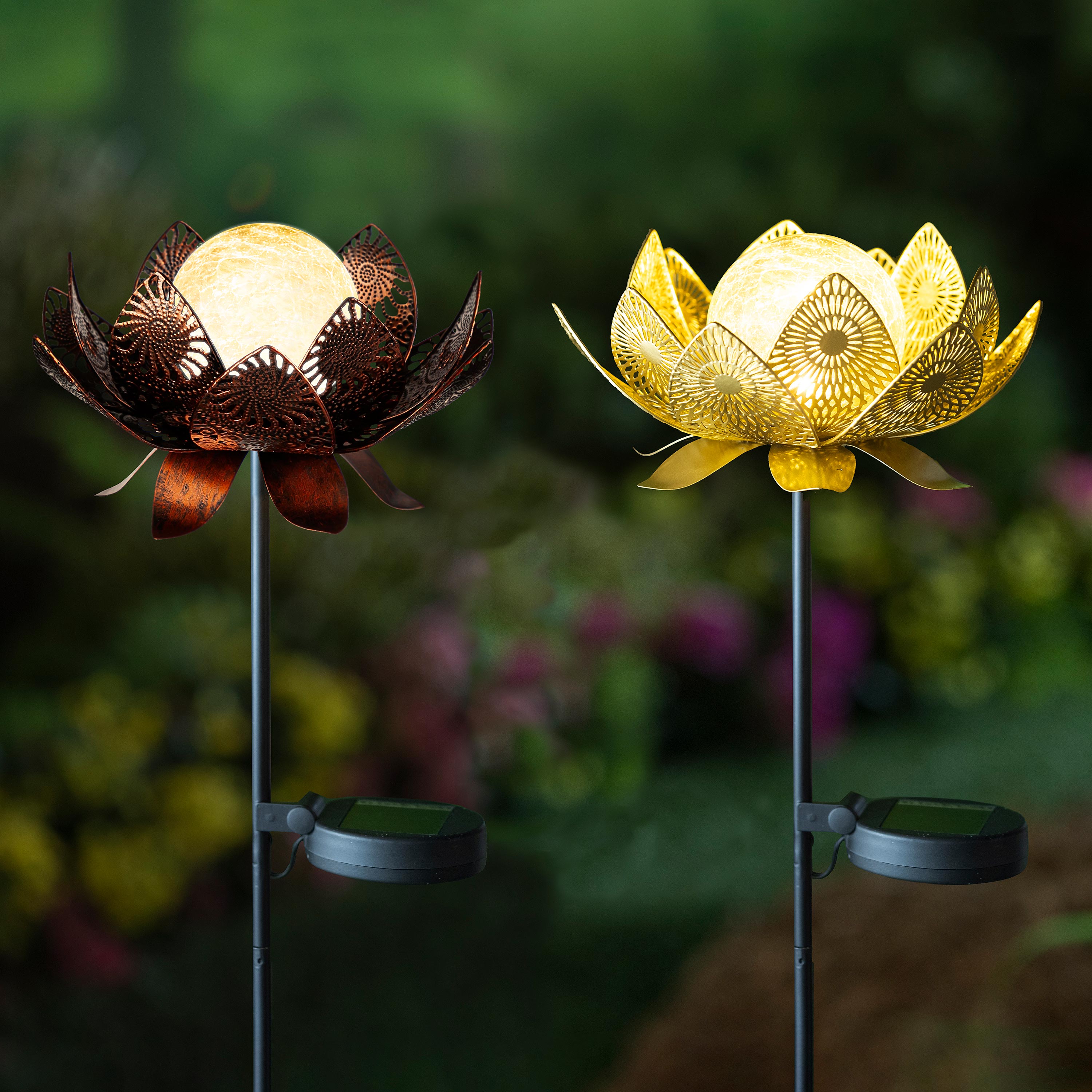 Two decorative garden stakes with lotus-shaped tops, one with a bronze finish and the other with a gold finish, set against a blurred garden background.
