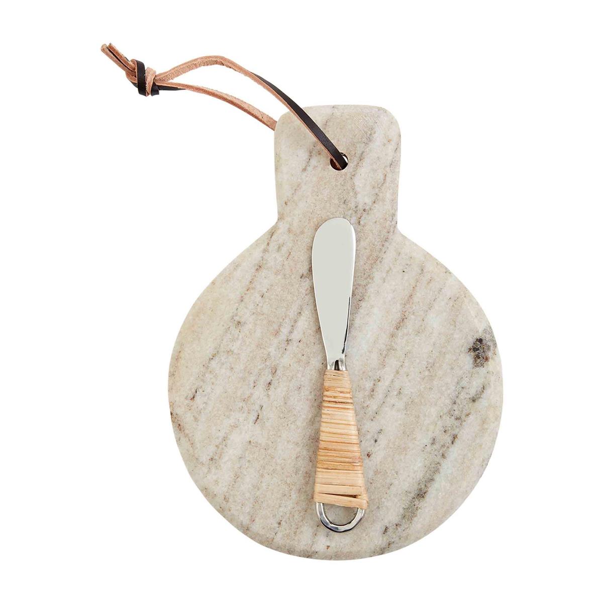A round beige marble cutting board with a metal handle and a leather strap attached.