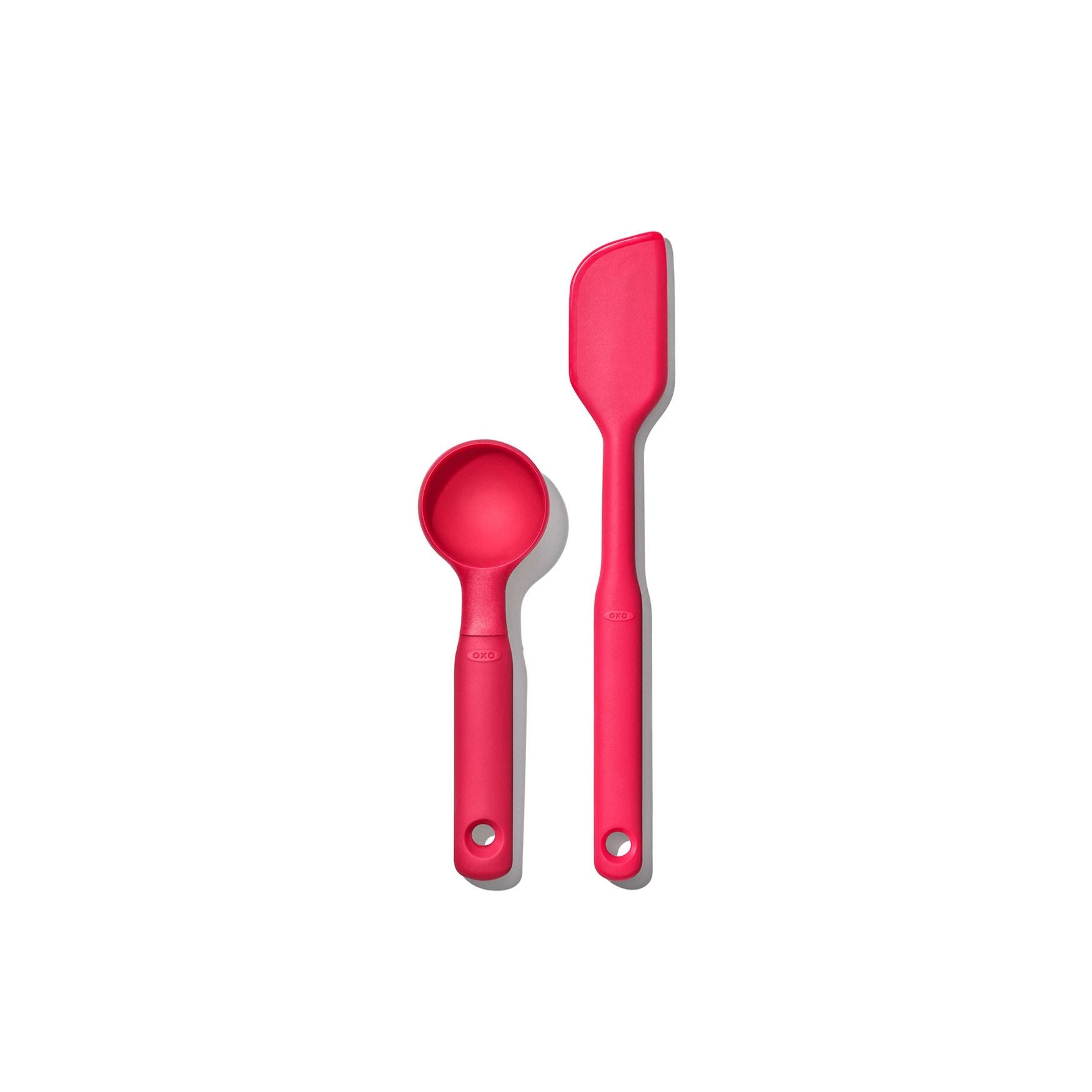 A pink OXO silicone cookie scoop and spatula set on a white background.