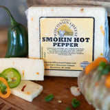 Block of Gardener's Wisconsin Cheese Smokin Hot Pepper with jalapeño slices on a wooden board.