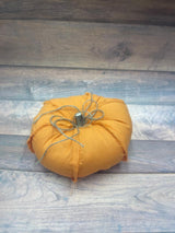 A handmade fabric pumpkin with an orange exterior, placed on a wooden surface.