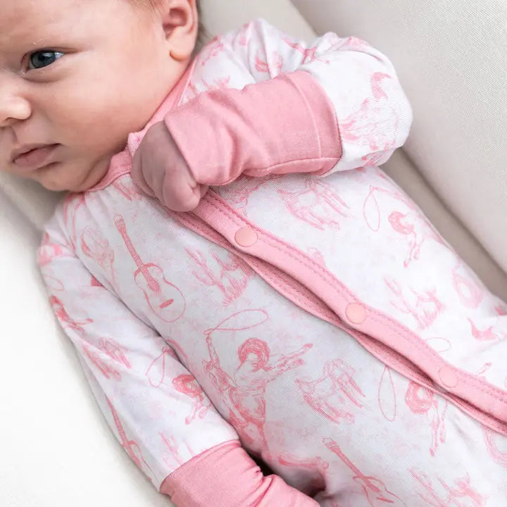 Baby in a pink and white patterned outfit lying on a light-colored surface