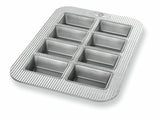 A silver mini loaf pan with eight sections, each lined with a non-stick material.