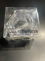 A clear, plastic garlic twist tool with a twisting mechanism, branded by NexTrend, intended for mincing garlic and other kitchen tasks.