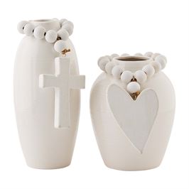 Two white stoneware vases with cross and heart designs, adorned with beads.