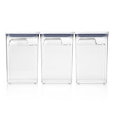 A set of three vertical, clear plastic bulk storage containers with blue lids, stacked on top of each other.