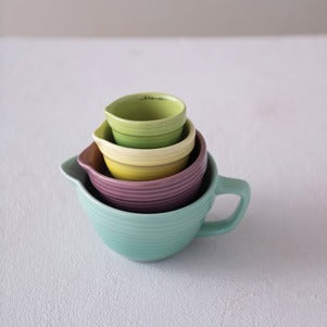Stack of colorful measuring ceramic cups on a white surface