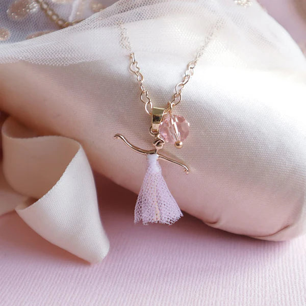 Necklace with a delicate pendant on a soft pink fabric background