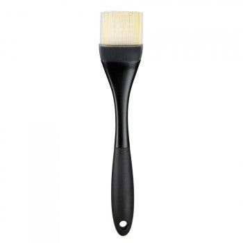 A large OXO silicone basting brush with a black handle and white bristles.