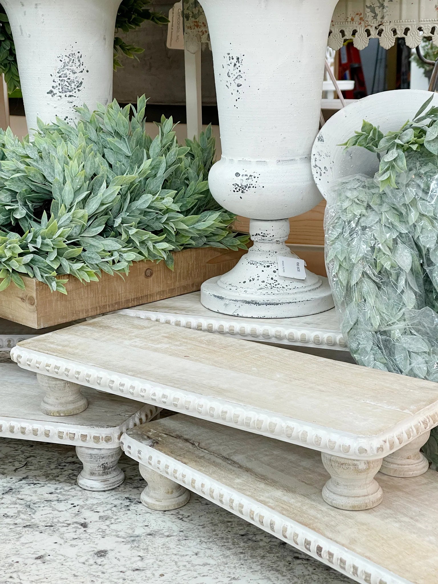 White distressed wooden shelves with decorative urns and greenery.
