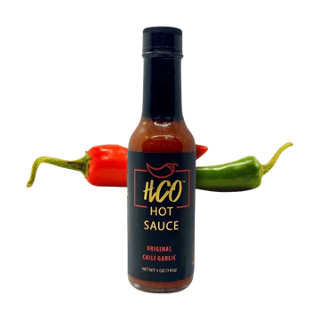 hot sauce in a bottle w peppers behind it