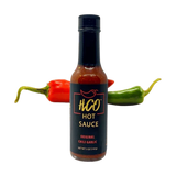 hot sauce in a bottle w peppers behind it
