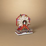 A decorative musical holiday ferris wheel with lights and a small figure on a base, intended for indoor use.