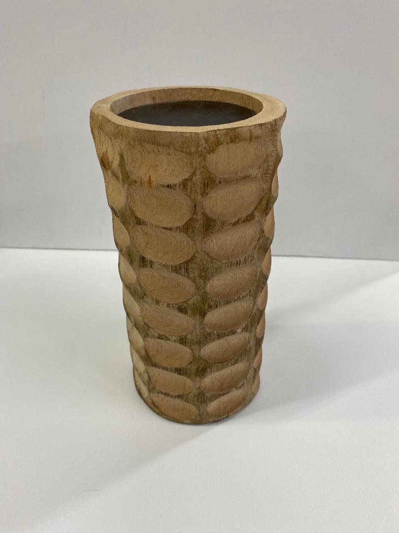A beige wooden candle holder with a chiseled texture