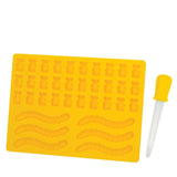 A yellow gelatin mold with cavities shaped like bears and worms, accompanied by a yellow dropper.