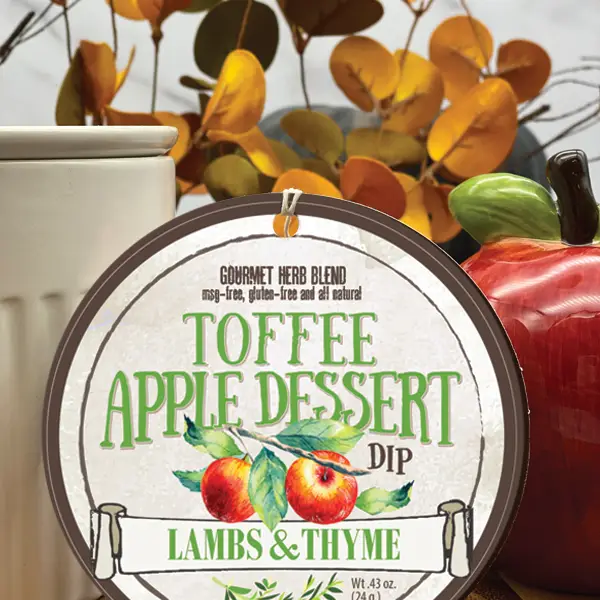 A packaged dessert dip labeled 'Toffee Apple Dessert Dip' from Lambs & Thyme, displayed with autumn leaves and fruits in the background.