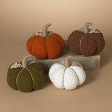 A set of plush harvest pumpkins in various colors including orange, brown, green, and white, arranged on a surface.