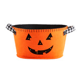 An orange felt bucket with a jack-o-lantern face printed on it, featuring black handles with a checkered pattern.