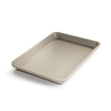 A beige non-stick quarter sheet baking pan with micro-textured surface, branded by OXO.