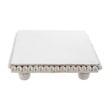 A square white trivet with a beaded edge, displayed on a neutral background.