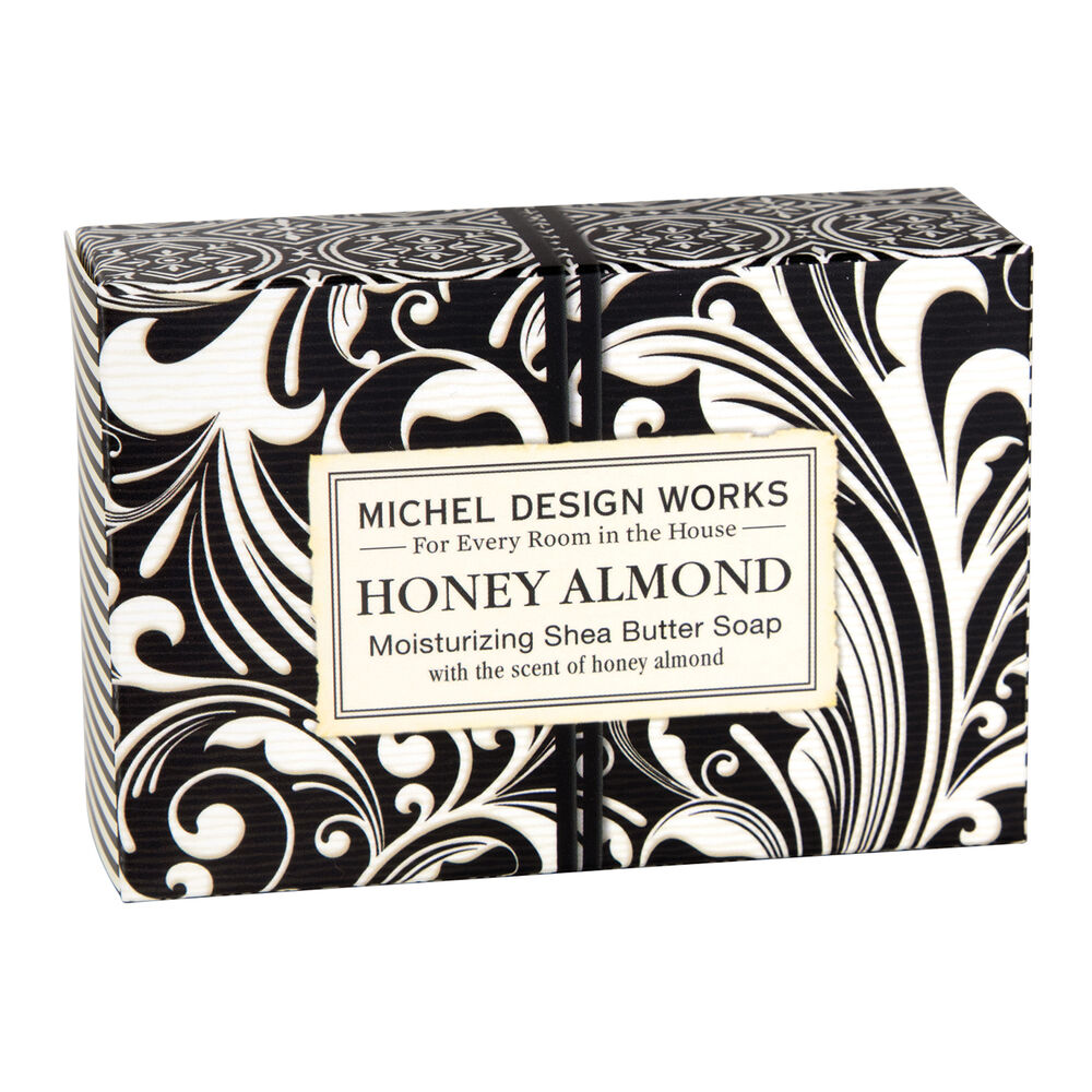 A bar of soap with a black and white floral patterned wrapper, labeled 'Michel Design Works Honey Almond Shea Butter Soap'.