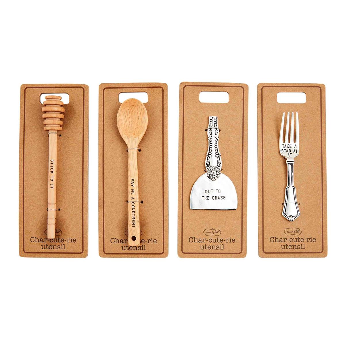 A set of tools for creating a charcuterie board, including a cheese utensil, wooden spreader, and two types of forks, all arranged in a line against a white background.