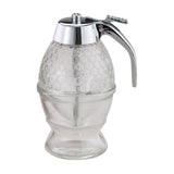 A clear glass honey jar with a metal dipper and pump, designed to resemble a beehive.