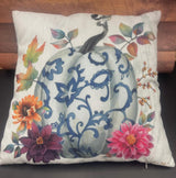 A decorative pillow with a pumpkin and floral design, predominantly featuring blue and pink colors.