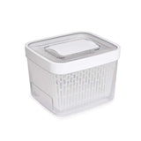 A clear plastic OXO GREENSAVER PRODUCE KEEPER with a white lid and removable baskets.