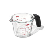 A clear glass measuring cup with red measurement markings and a black handle, with a 4 cup capacity.