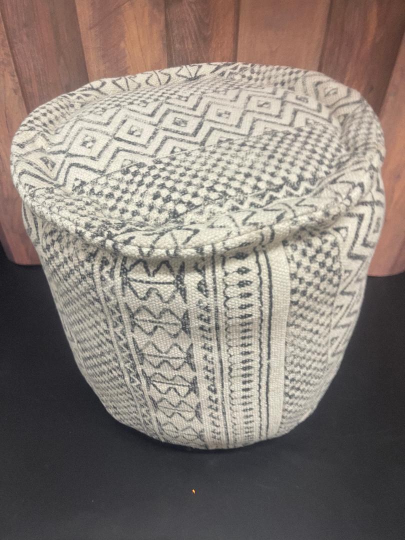 A round charcoal gray pouf with a bohemian pattern.