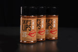 Three bottles of Skip's Lips rim salt seasoning, placed side by side on a dark surface.