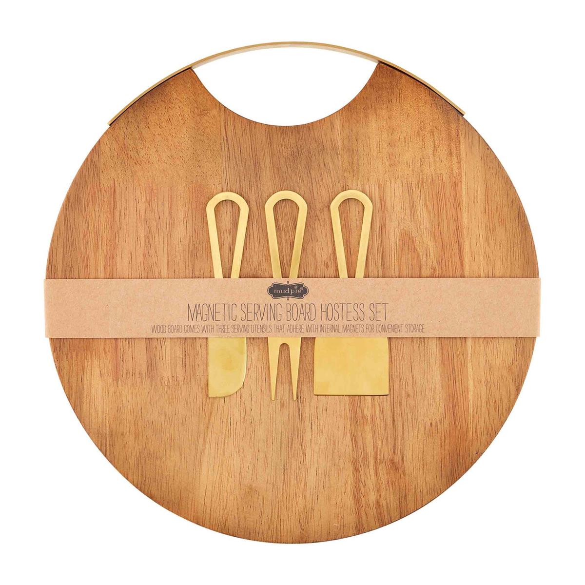 A round wooden serving board with a magnetic surface, accompanied by a set of three metal utensils (a spoon, fork, and knife), packaged with a beige band.