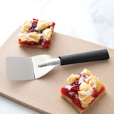 Two slices of cherry pie with a spatula on a wooden board.