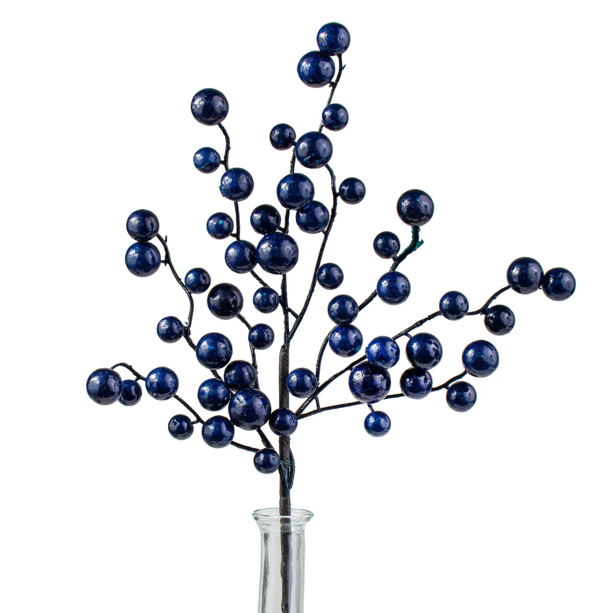 Artificial navy blue berry branch decor with glossy dark blue round berries on thin dark stems, displayed in a clear glass vase against a white background.