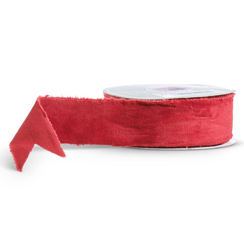 A roll of red velvet ribbon with a piece partially unrolled, displaying the soft, velvety texture.
