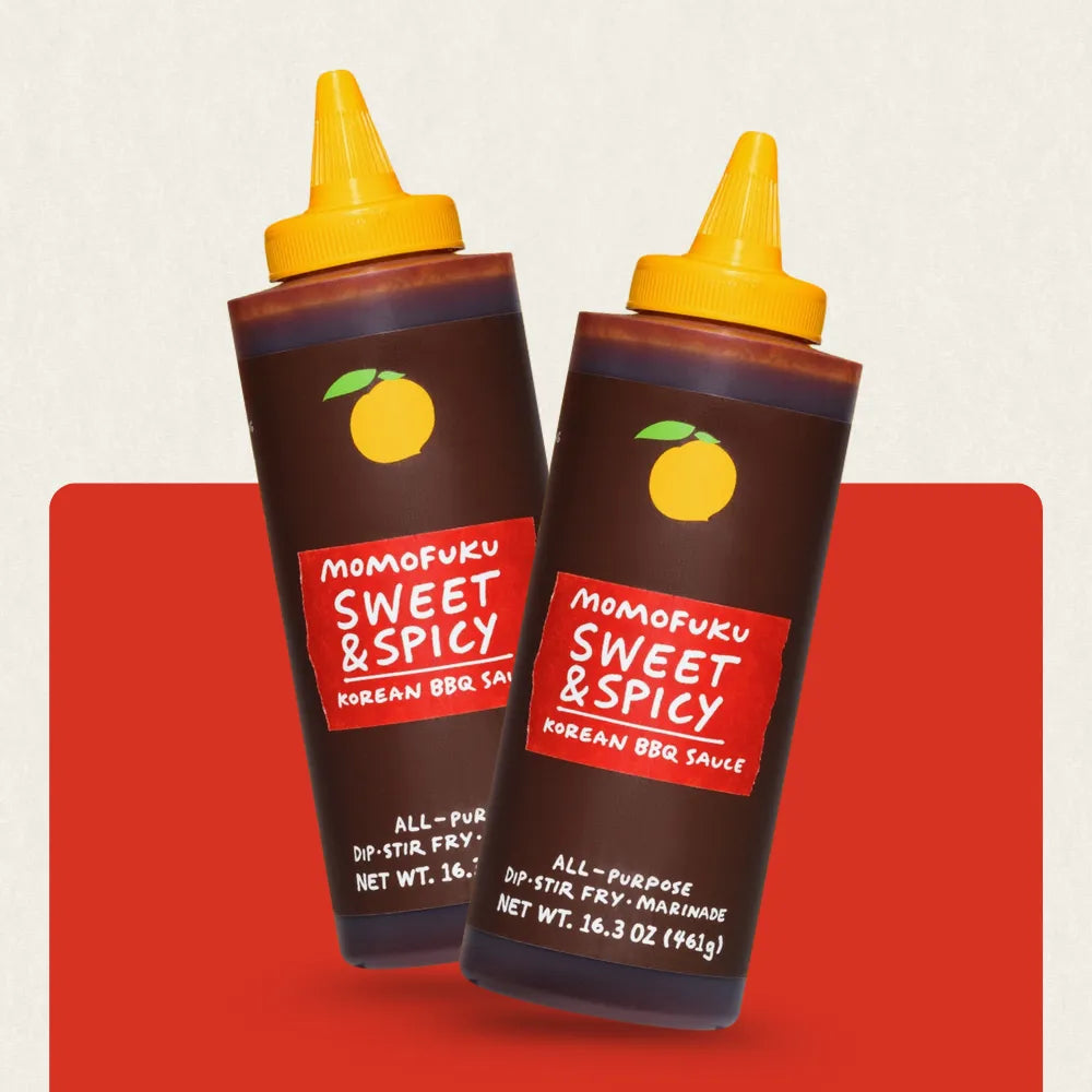 Two bottles of Momofuku Sweet & Spicy Korean BBQ Sauce on a red background
