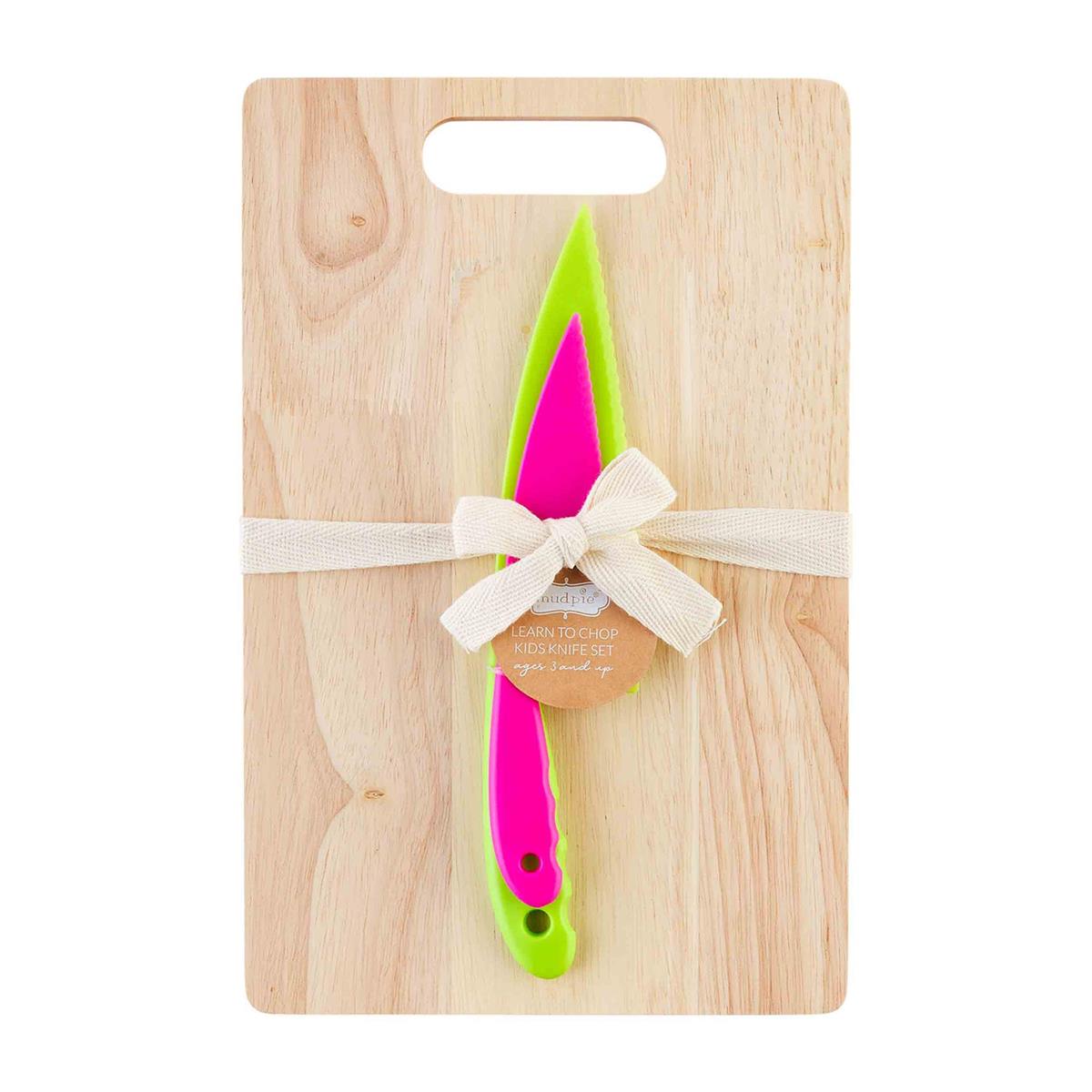 A plastic knife with a pink handle, attached to a wooden cutting board with a white ribbon and a bow.