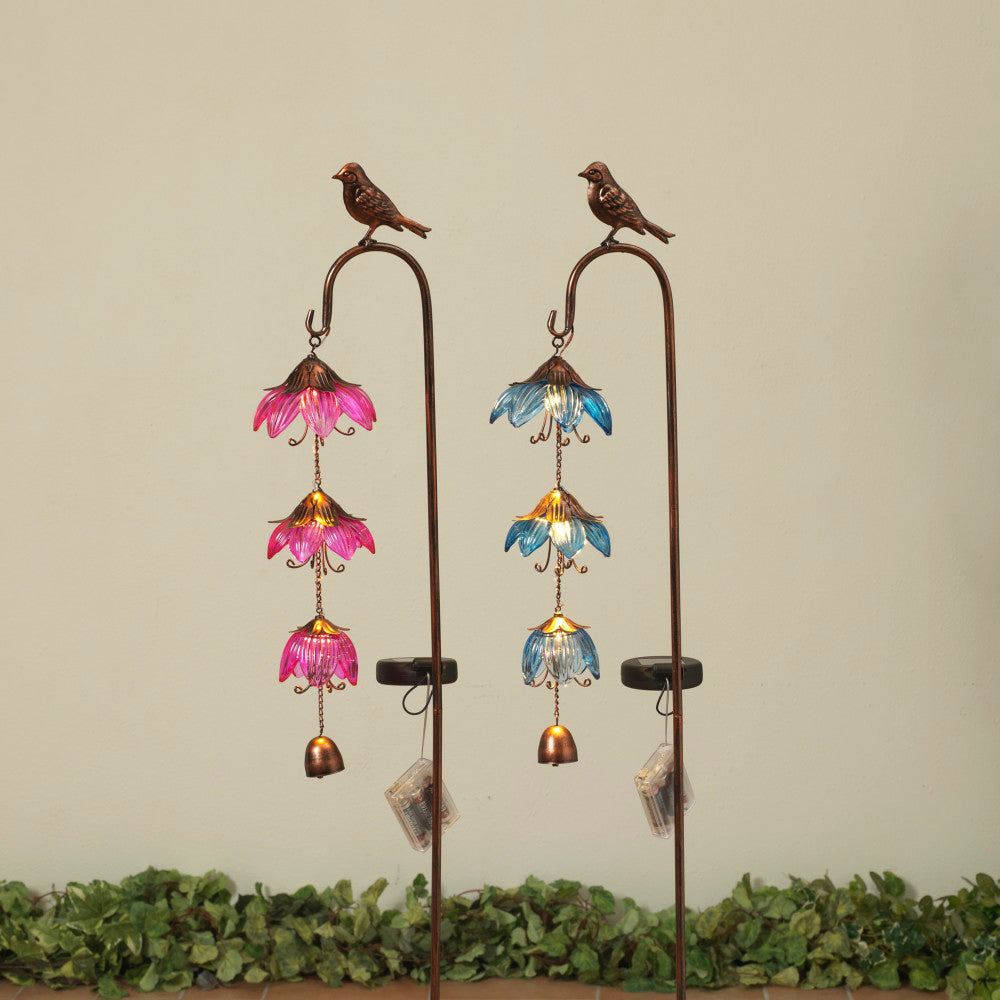 Two solar lighted metal and glass stakes with bird designs and colorful flower-like patterns, displayed against a neutral background with foliage at the bottom.