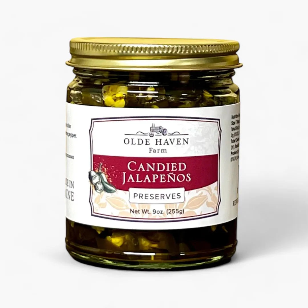 A jar of Olde Haven Farm Candied Jalapeños Preserves with a gold metal lid and a white label featuring a red banner, set against a plain white background.