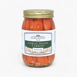 A jar of Olde Haven Farm Garlic Honey Carrots Pickles, featuring bright orange carrots in a glass jar with a gold metal lid and a white label with green and beige accents.