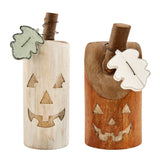 Two wooden pumpkin block sitters with carved faces, one in light beige and the other in brown, both with leaf-shaped accents.